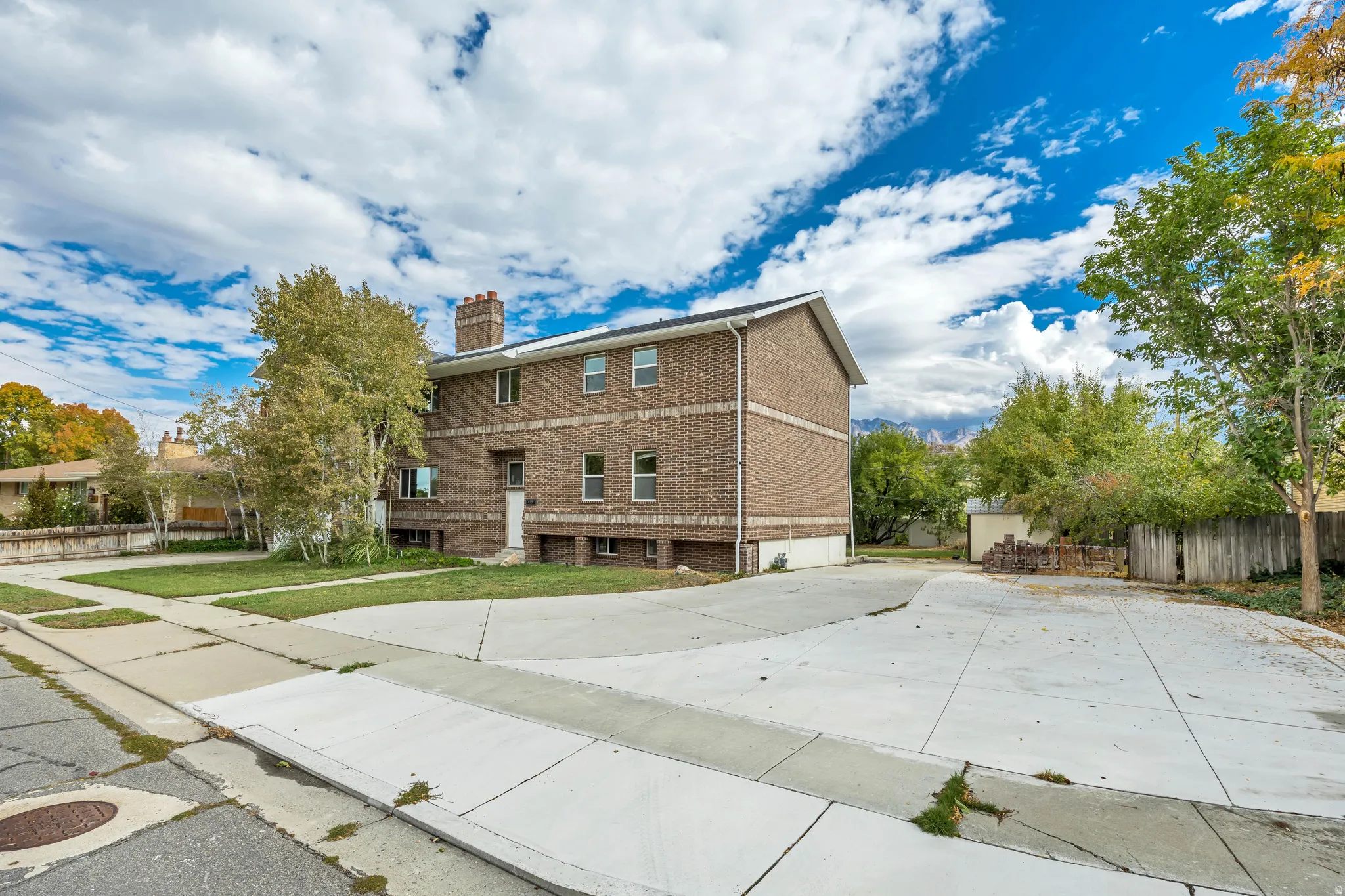 Back of property with brick siding, a chimney, and concrete driveway