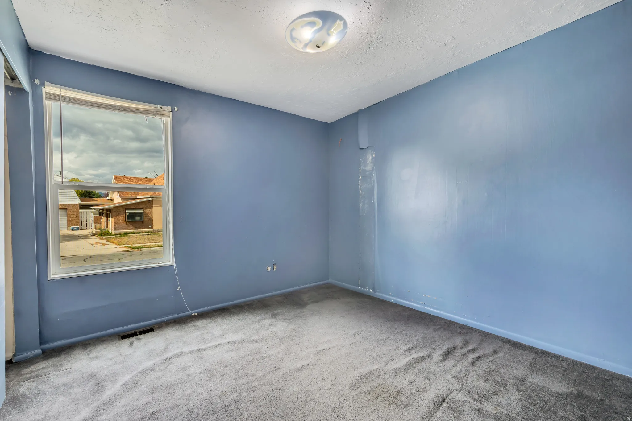 Carpeted spare room featuring a textured ceiling and baseboards