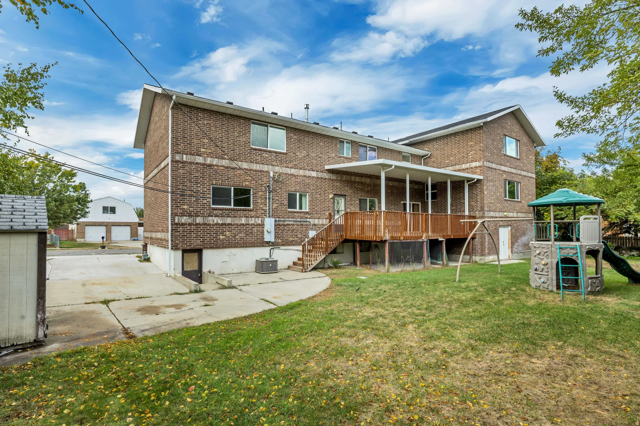 Rear view of house with a lawn, brick siding, a deck, and stairs