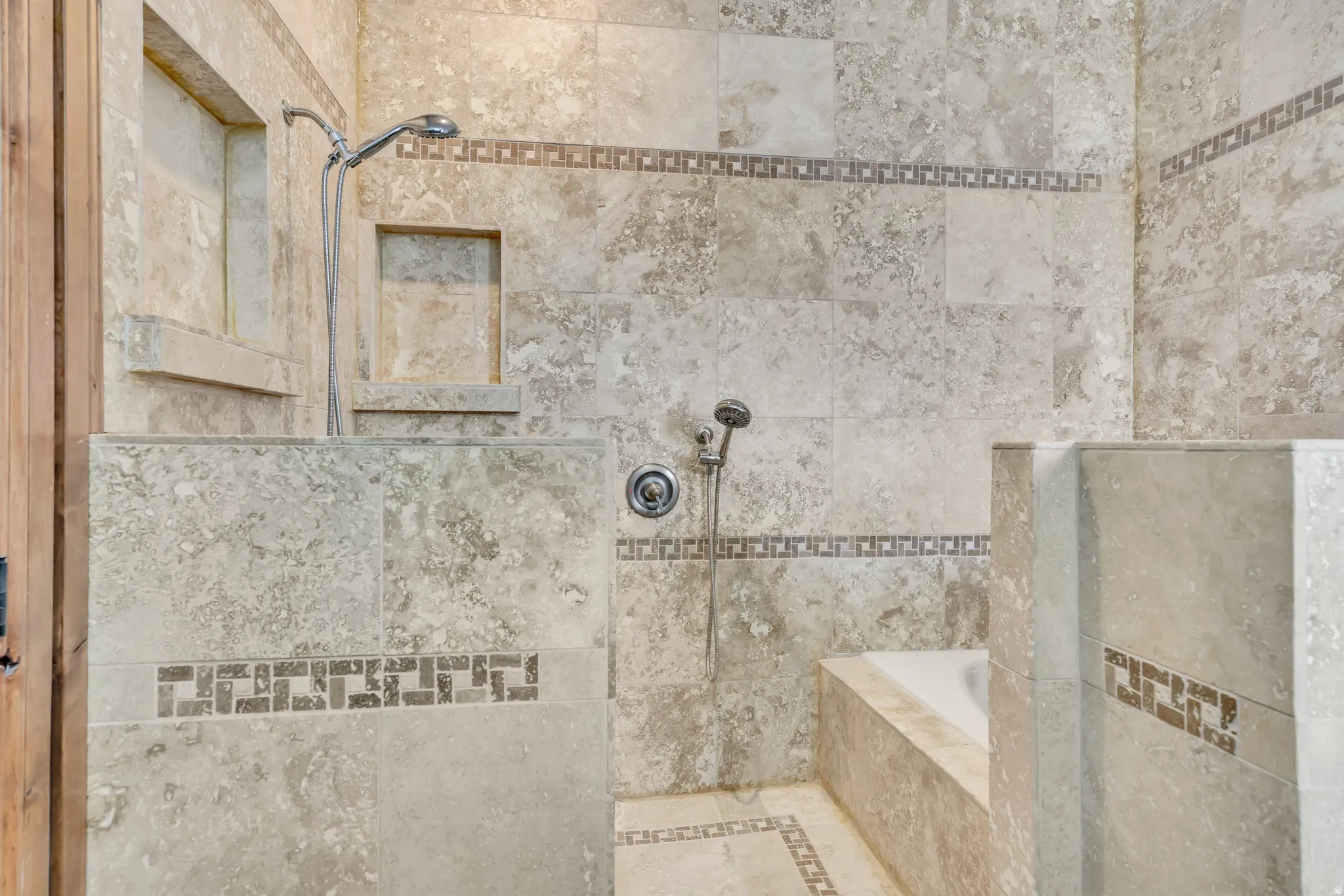 Bathroom featuring tiled shower, inlaid floor details, and a relaxing tiled tub
