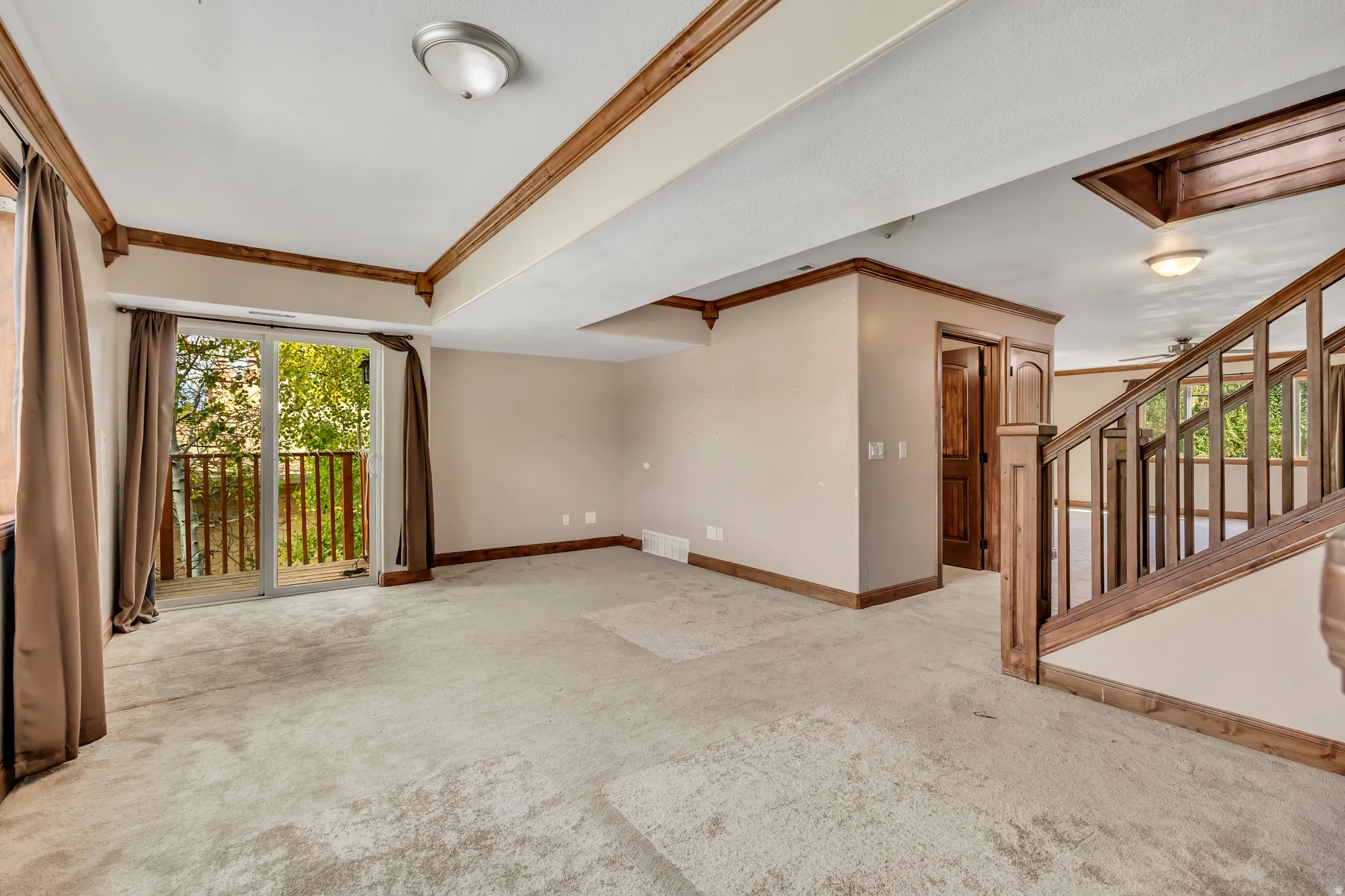 Unfurnished room featuring crown molding, light colored carpet, and stairway