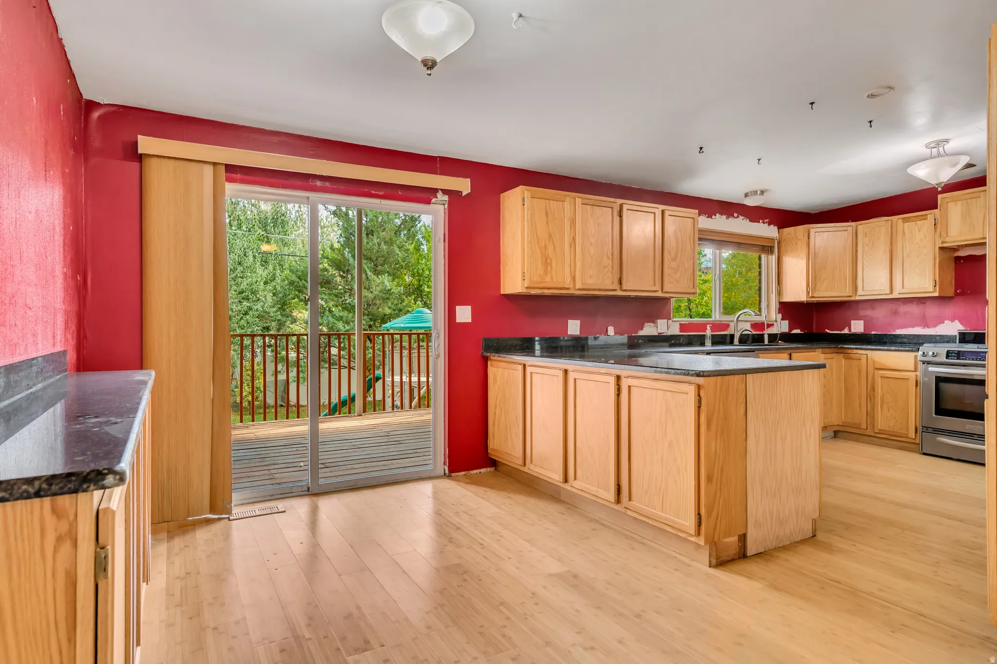 Kitchen with a peninsula, stainless steel range, light wood-style flooring, and light brown cabinets