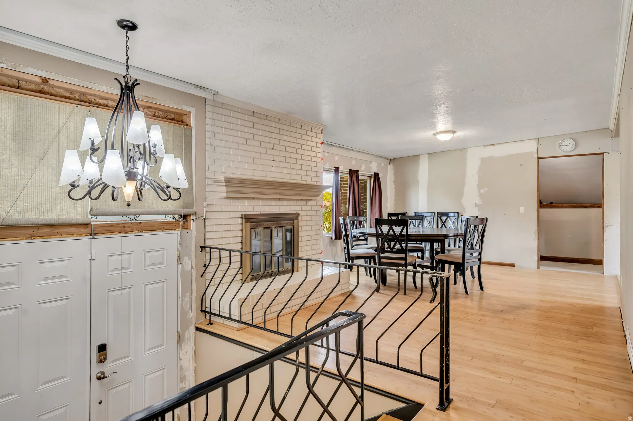 Dining area with a chandelier, light wood-type flooring, a fireplace, and a textured ceiling