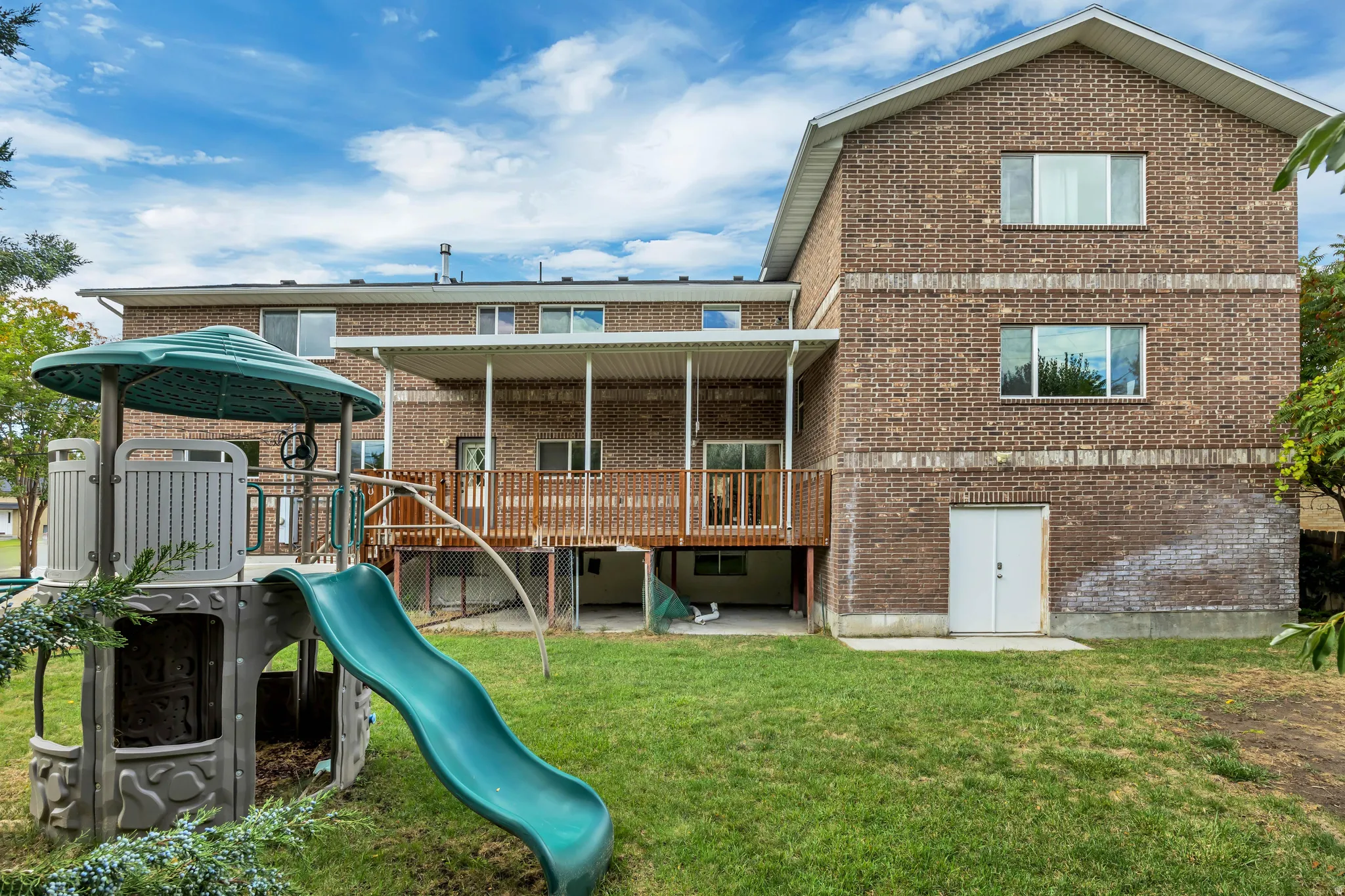 Back of property featuring brick siding, a patio area, and a yard