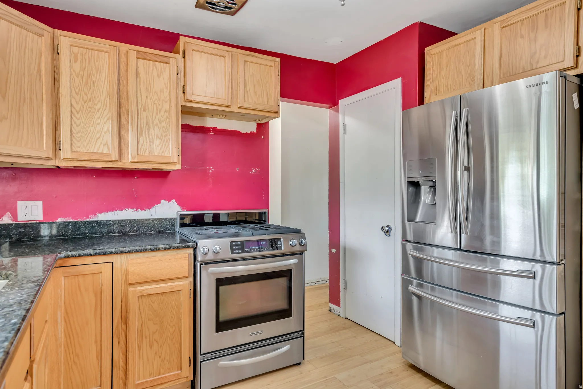 Kitchen featuring light brown cabinetry, appliances with stainless steel finishes, and dark countertops