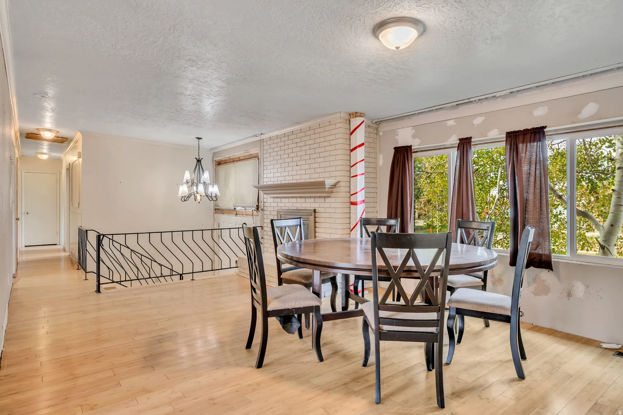 Dining room featuring a textured ceiling, light wood-style floors, a fireplace, and a chandelier