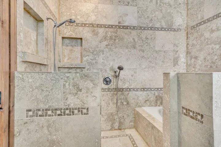 Bathroom featuring tiled shower, inlaid floor details, and a relaxing tiled tub