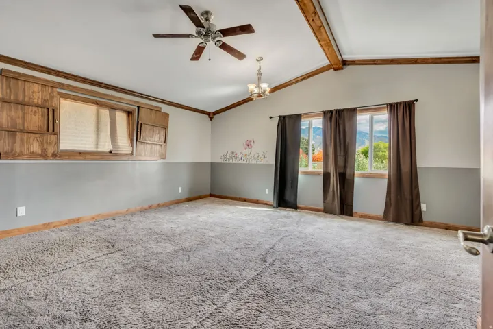 Unfurnished room with carpet, a ceiling fan, a chandelier, and ornamental molding
