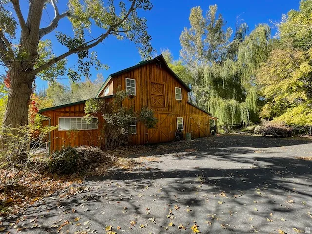 View of home's exterior with a barn, an outbuilding, a garage, and asphalt driveway