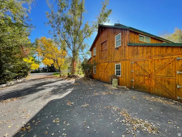 View of side of property with a barn, an outbuilding, a garage, and asphalt driveway