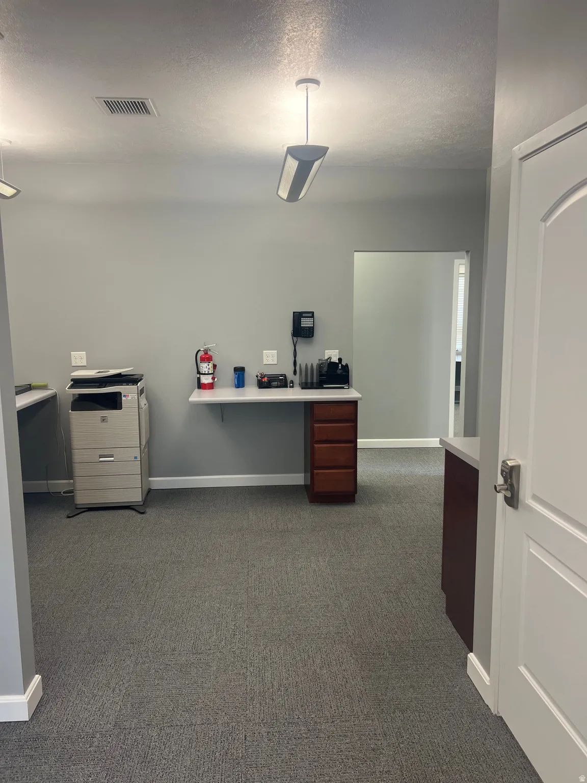 Office area featuring a textured ceiling and dark colored carpet