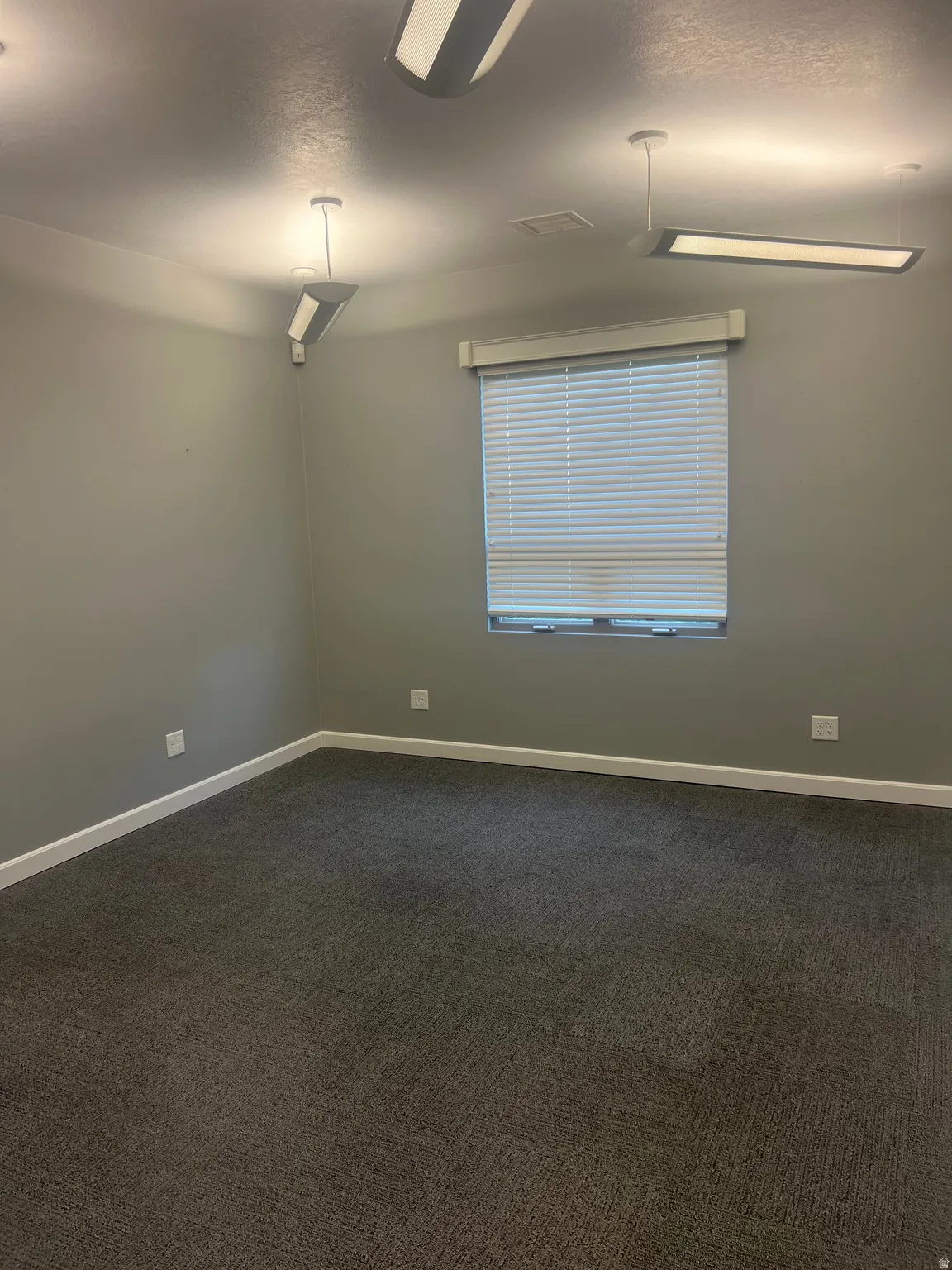 Unfurnished room with dark colored carpet and a textured ceiling