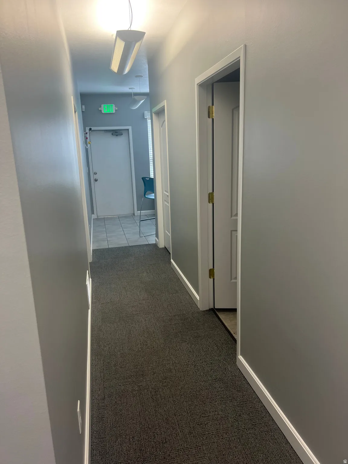 Hallway featuring dark colored carpet and baseboards