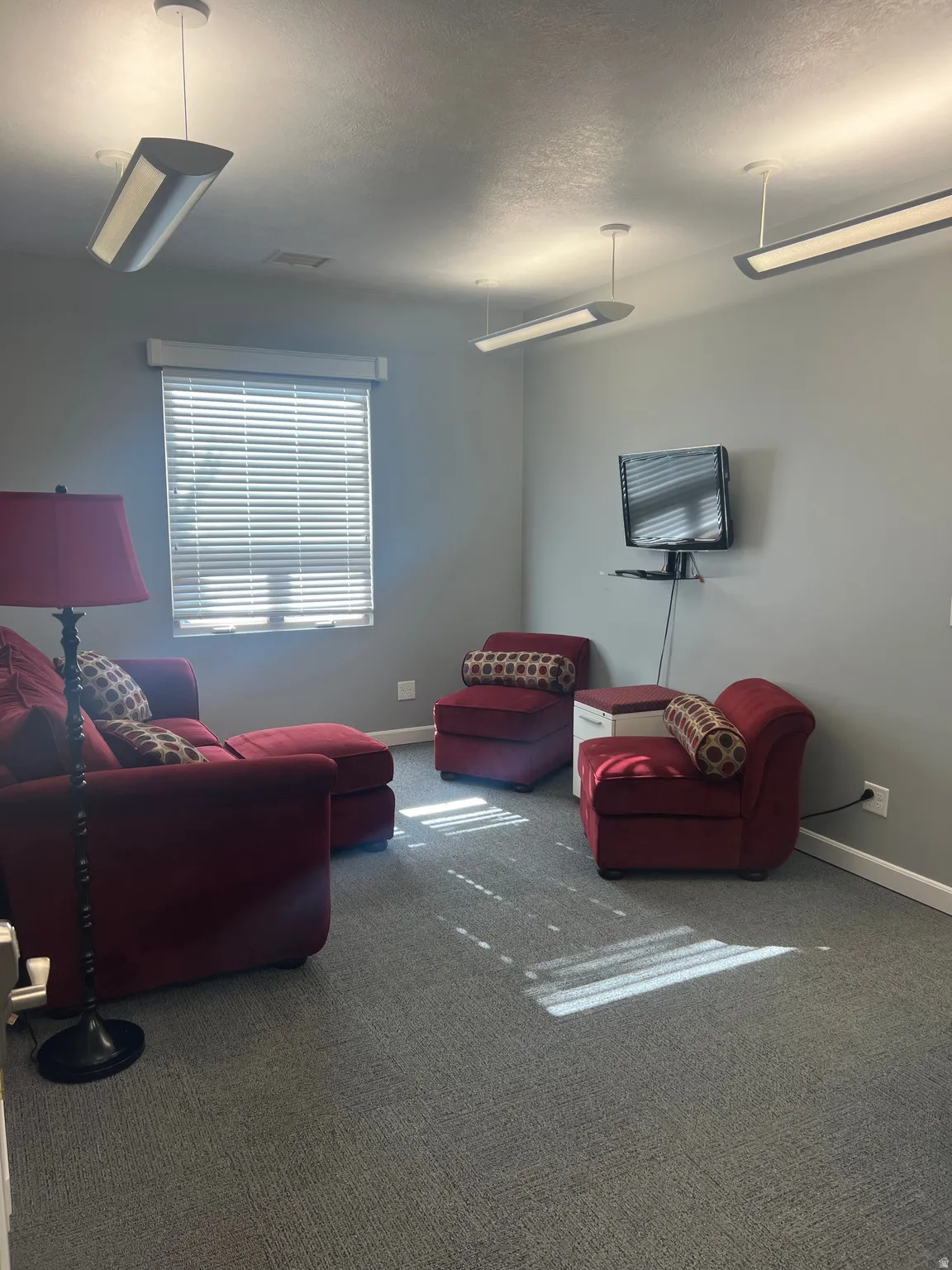 Carpeted living area featuring baseboards and a textured ceiling