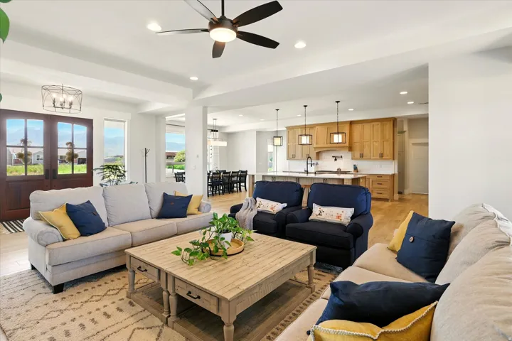 Living room featuring recessed lighting, light wood finished floors, a ceiling fan, a chandelier, and french doors