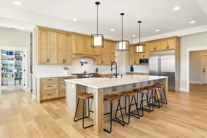 Kitchen featuring light brown cabinets, a breakfast bar, built in appliances, and recessed lighting