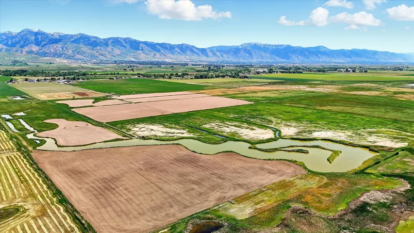 View of rural area featuring extensive farmland and a mountain backdrop and water