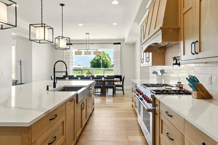 Kitchen featuring stainless steel appliances, hanging light fixtures, light stone counters, recessed lighting, and light wood-style floors