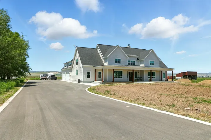 View of front facade with covered porch, a garage, roof with shingles, and driveway