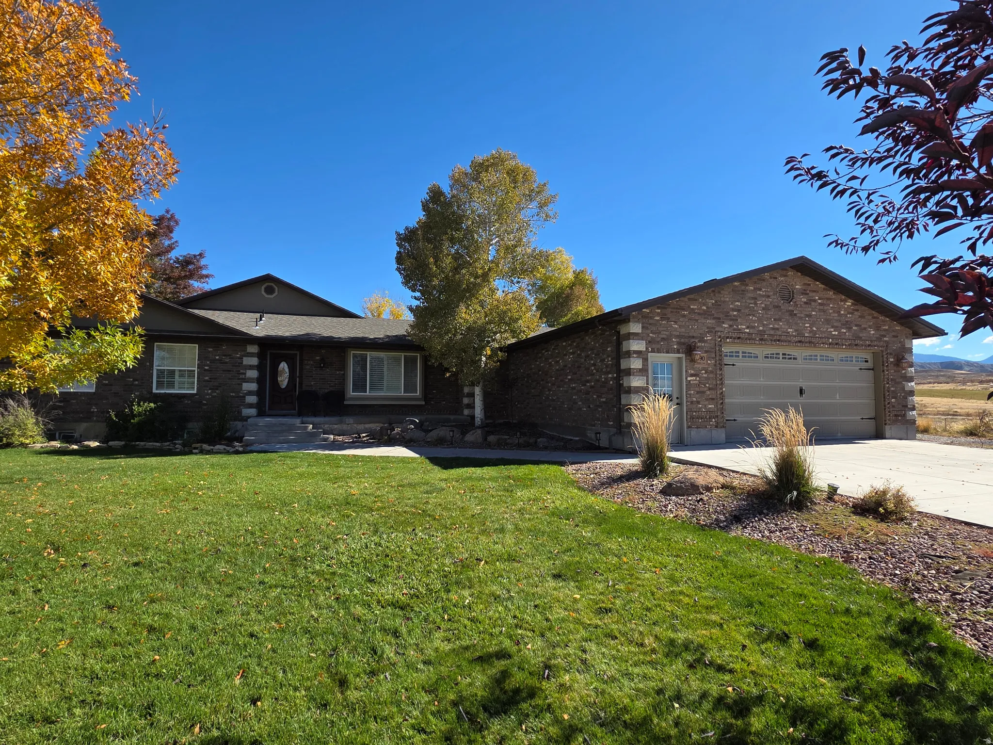 Ranch-style home featuring brick siding, driveway, a front yard, and a garage