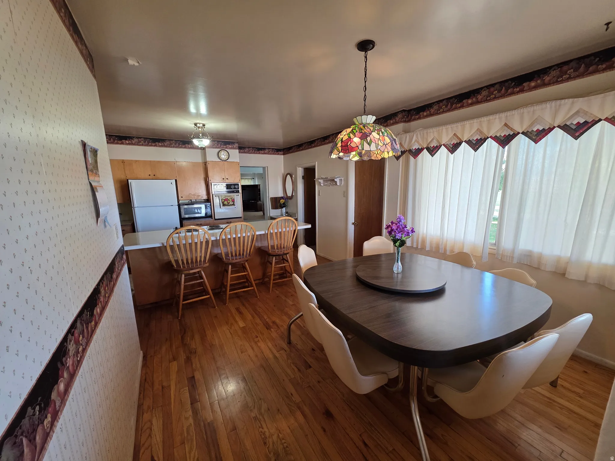 Dining space featuring wallpapered walls and dark wood-style floors