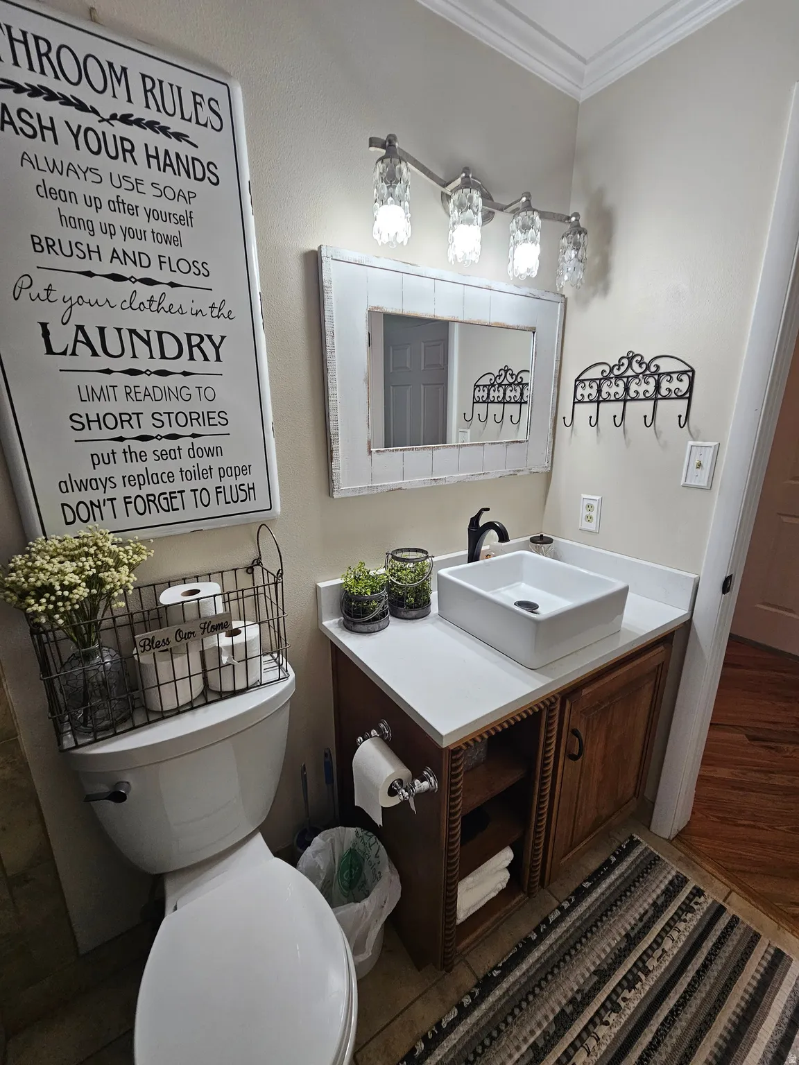 Half bathroom featuring vanity, crown molding, and wood finished floors