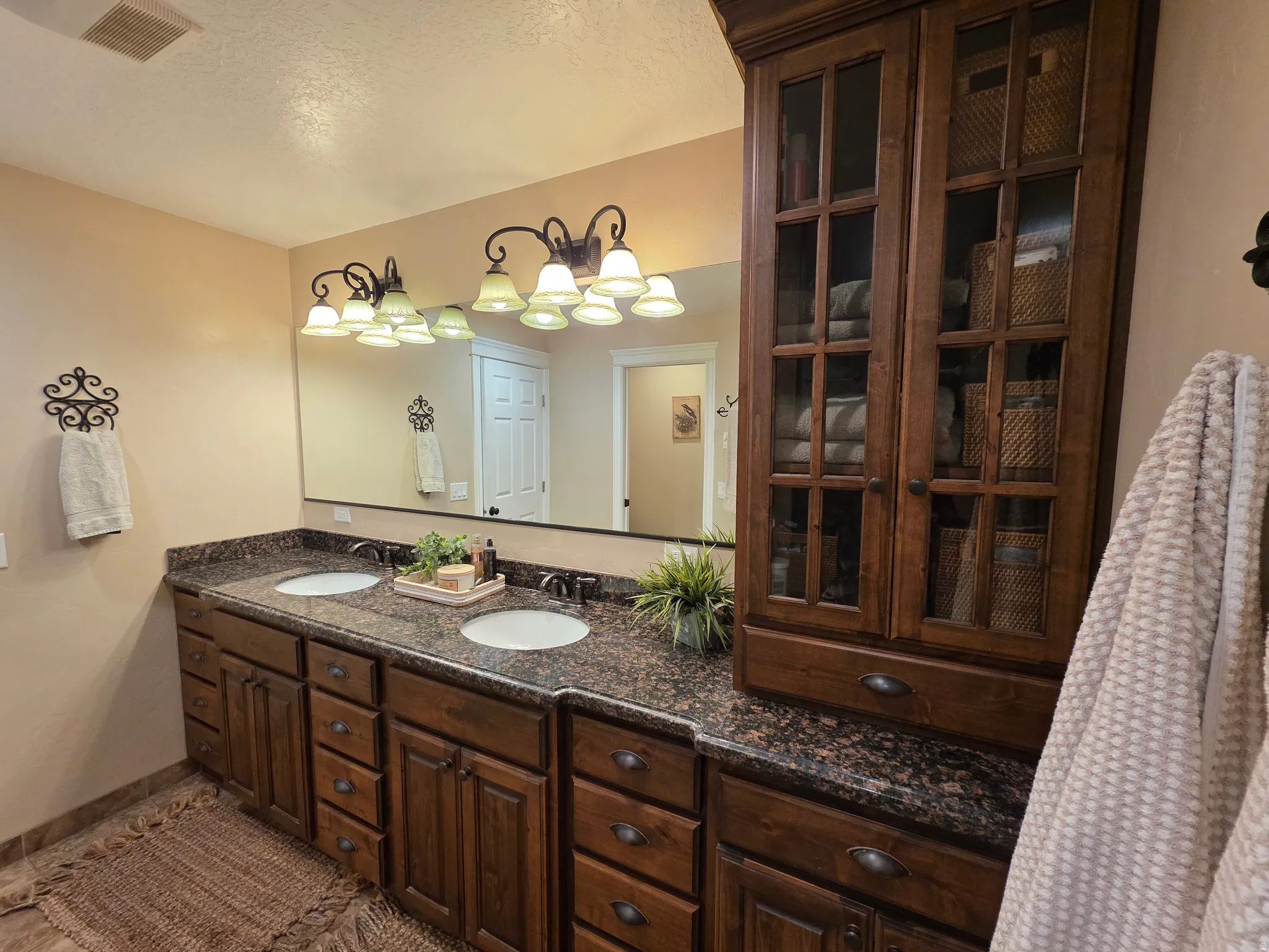 Bathroom with double vanity, a textured ceiling, and tile patterned floors