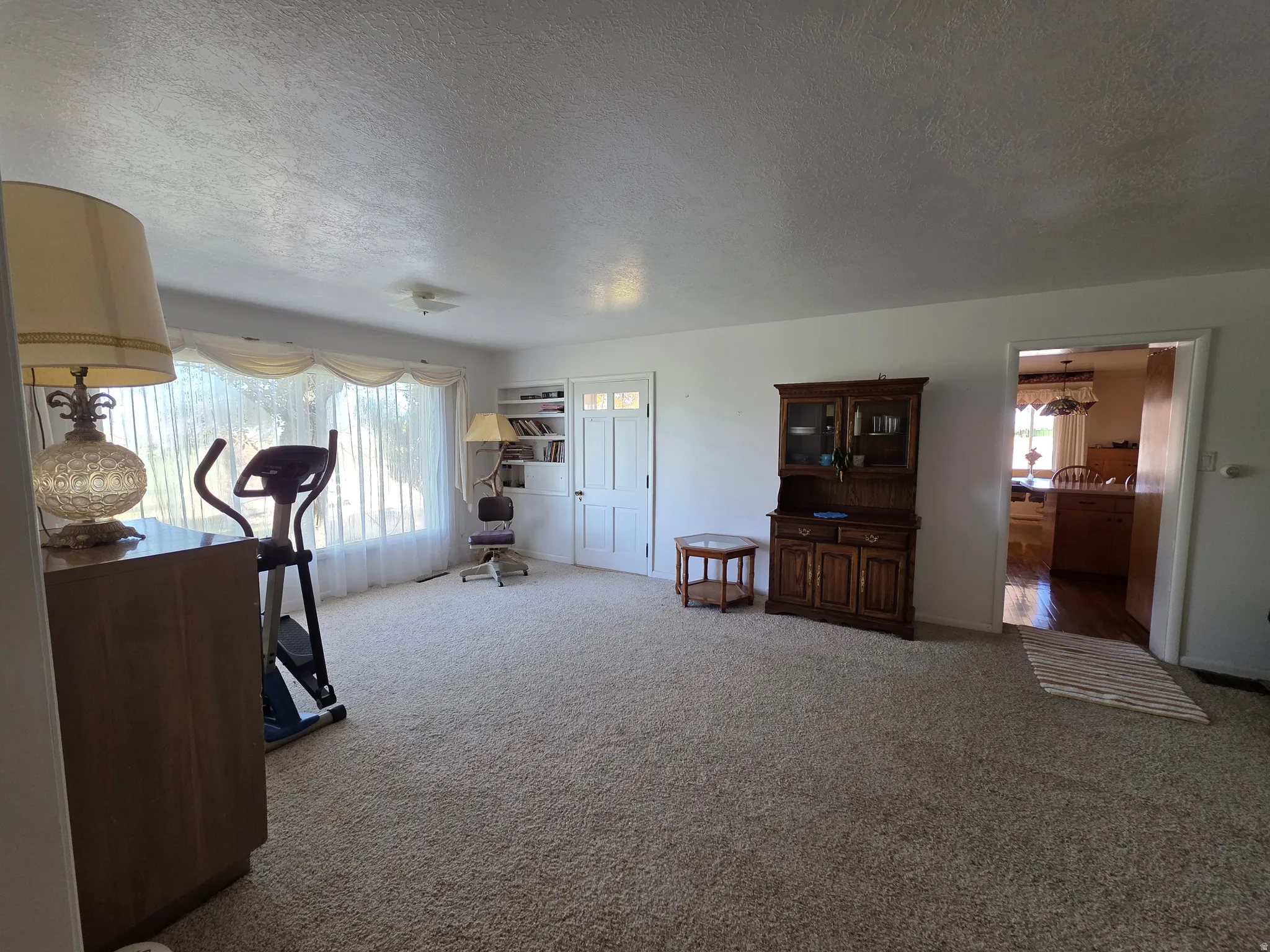 Exercise room with light colored carpet and a textured ceiling