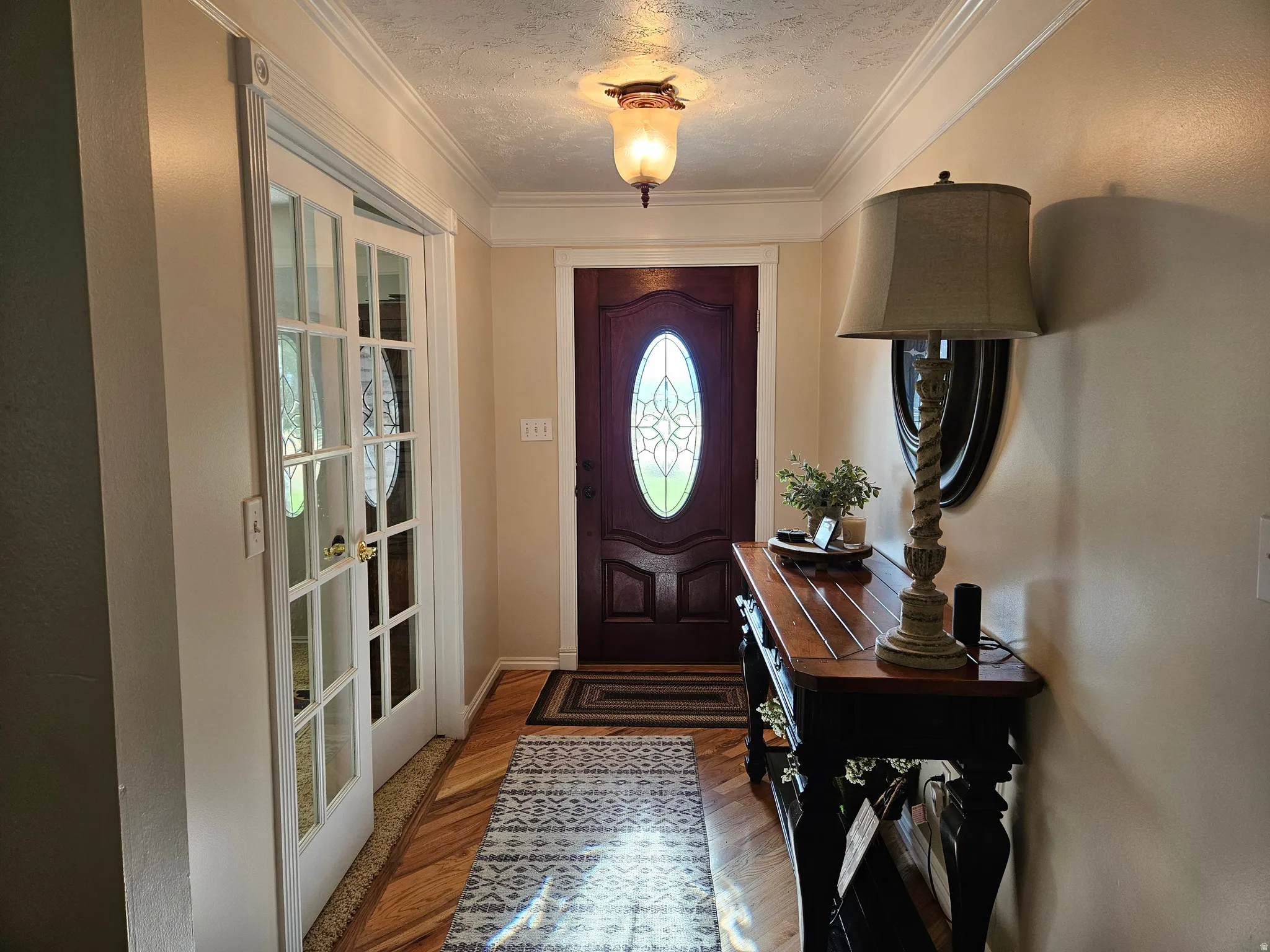 Entryway featuring ornamental molding, dark wood finished floors, and a textured ceiling