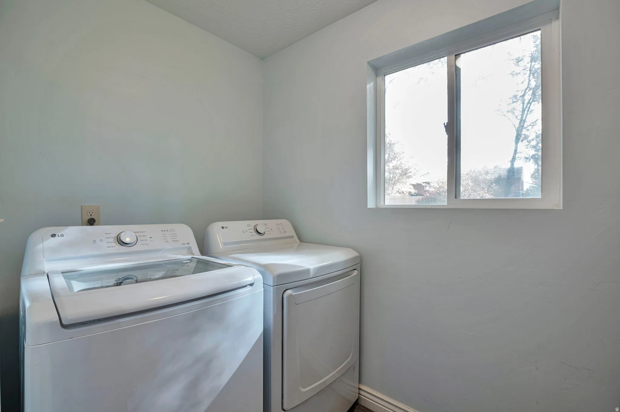 Laundry area with separate washer and dryer and baseboards
