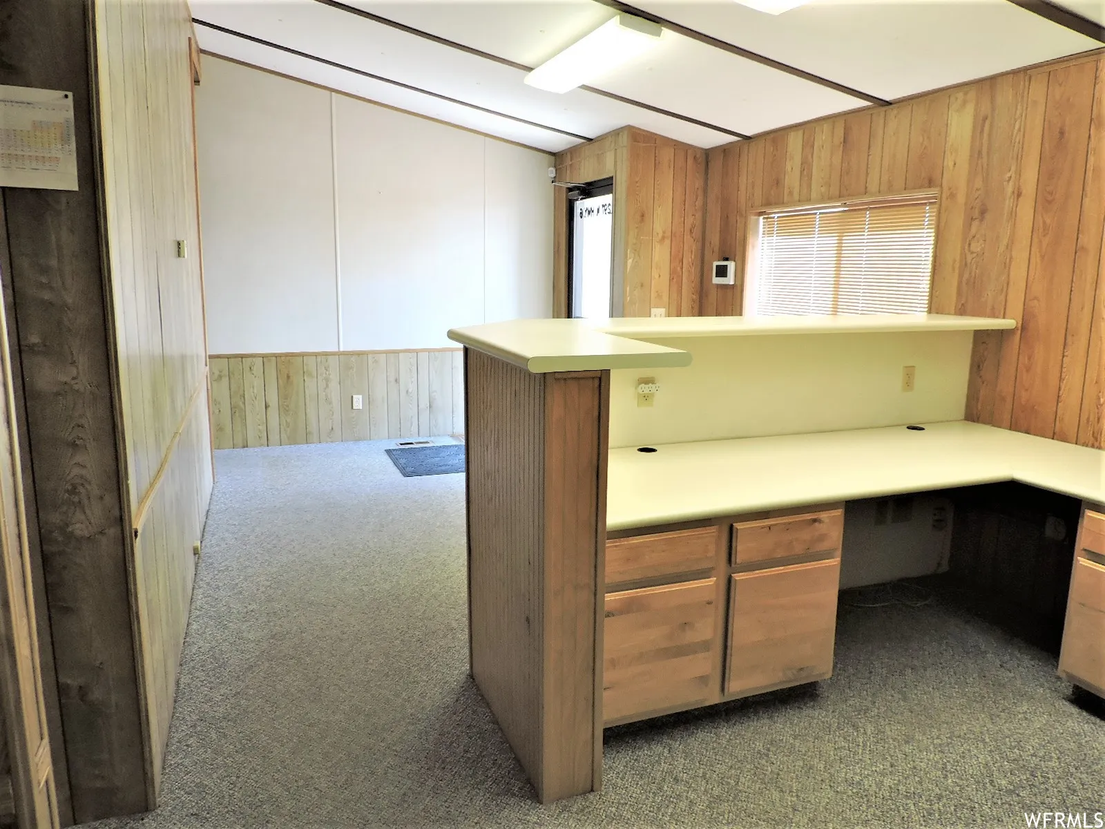 Unfurnished lobby with wooden walls, dark carpet, and built in study area