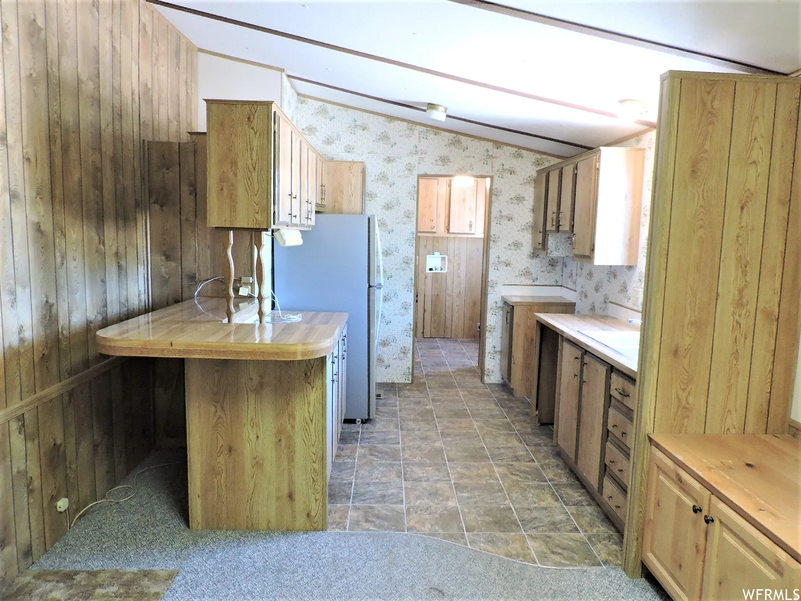 Kitchen featuring lofted ceiling and freestanding refrigerator