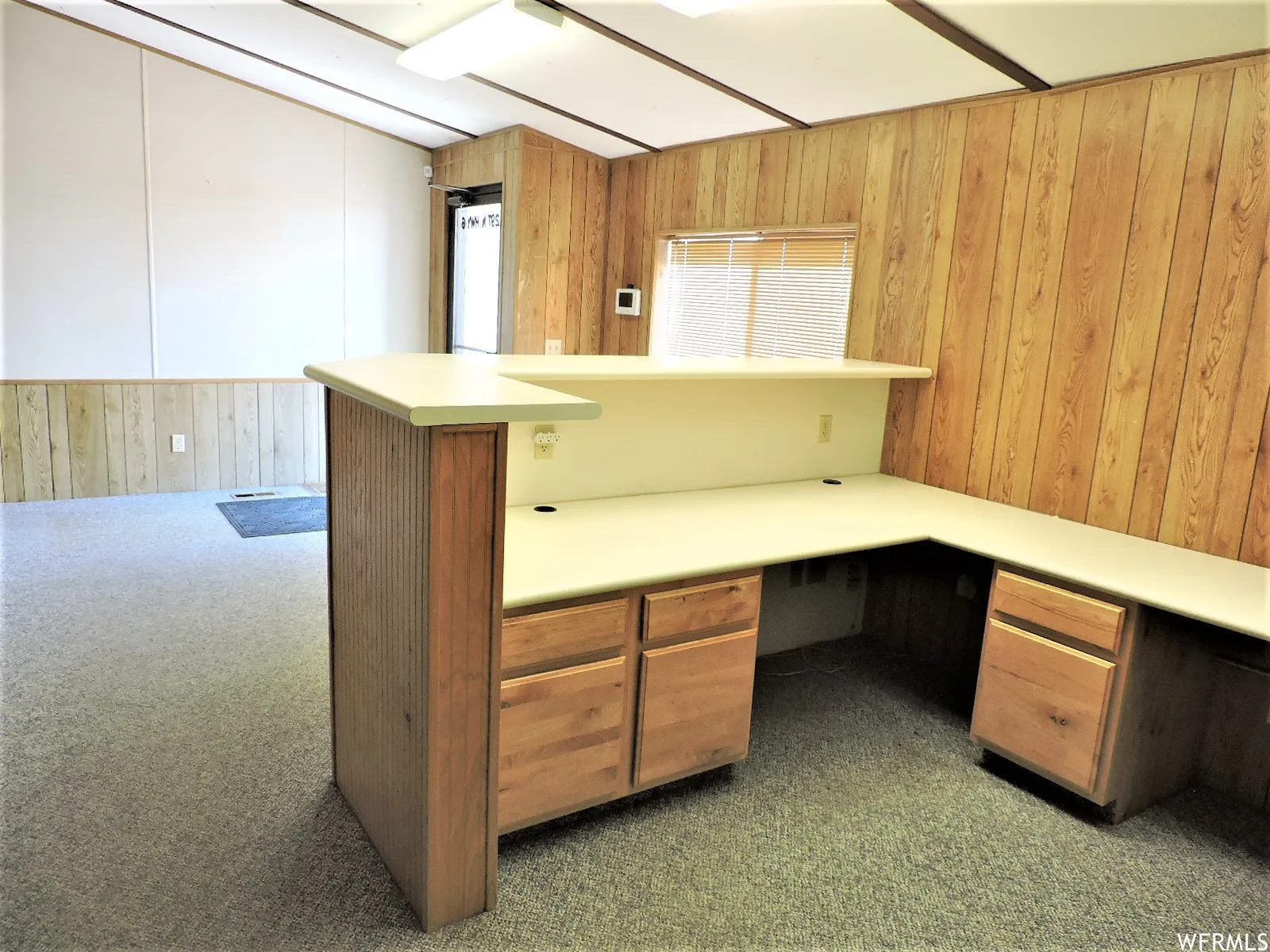 Unfurnished lobby featuring built in desk, wooden walls, and dark carpet