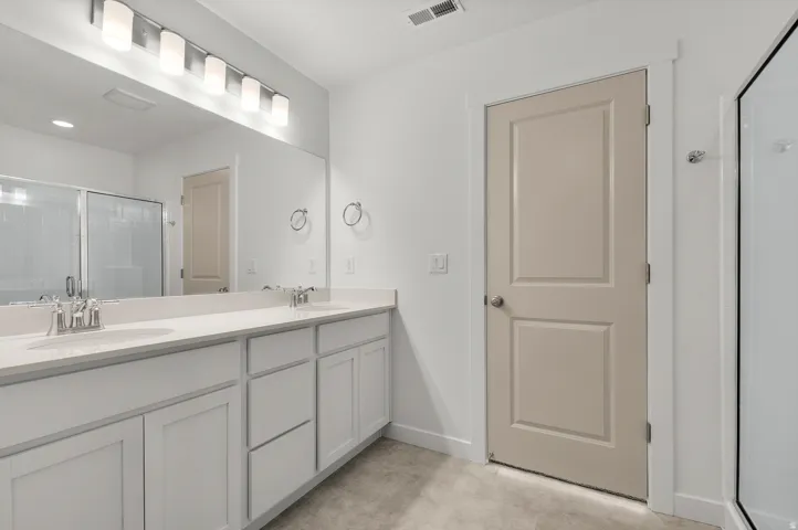 Full bath with a shower stall and double vanity