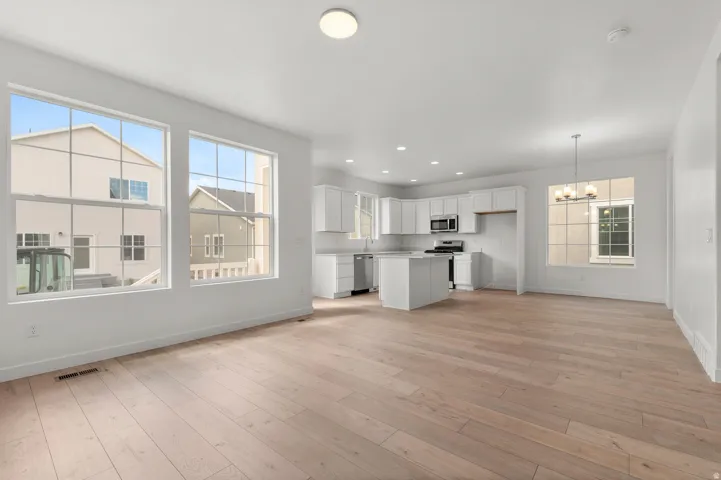 Unfurnished living room with plenty of natural light, a chandelier, light wood-style floors, and recessed lighting