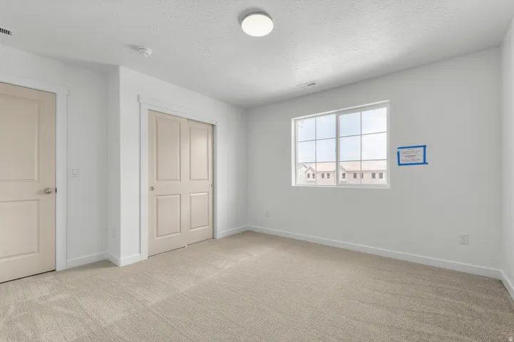 Unfurnished bedroom featuring light colored carpet, a closet, and a textured ceiling