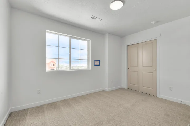 Unfurnished bedroom featuring light carpet, a closet, and a textured ceiling