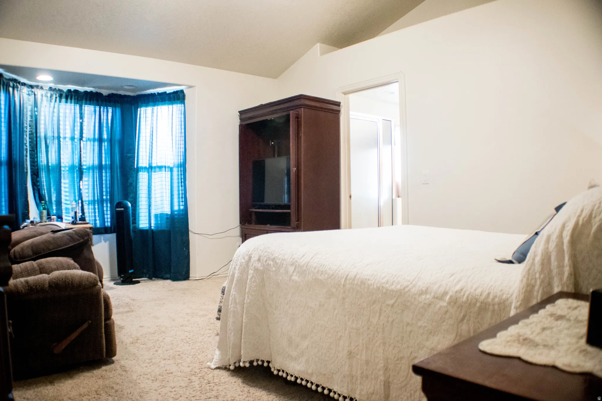 Bedroom with light carpet and vaulted ceiling