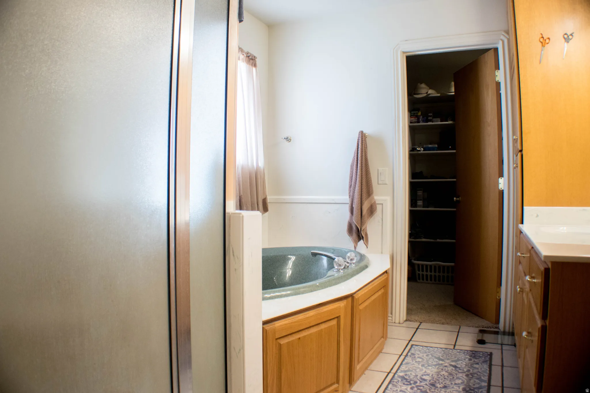 Full bathroom with vanity, light tile patterned flooring, a bath, a shower stall, and a spacious closet