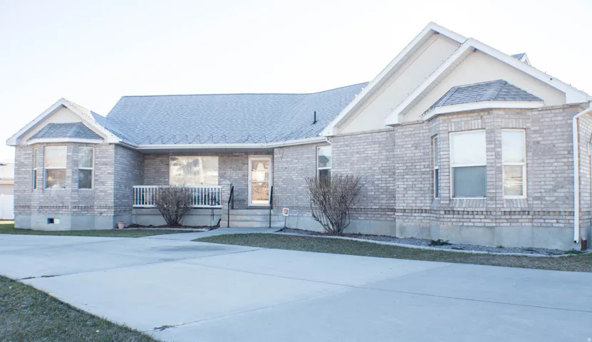 View of front of home featuring brick siding, a shingled roof, and covered porch