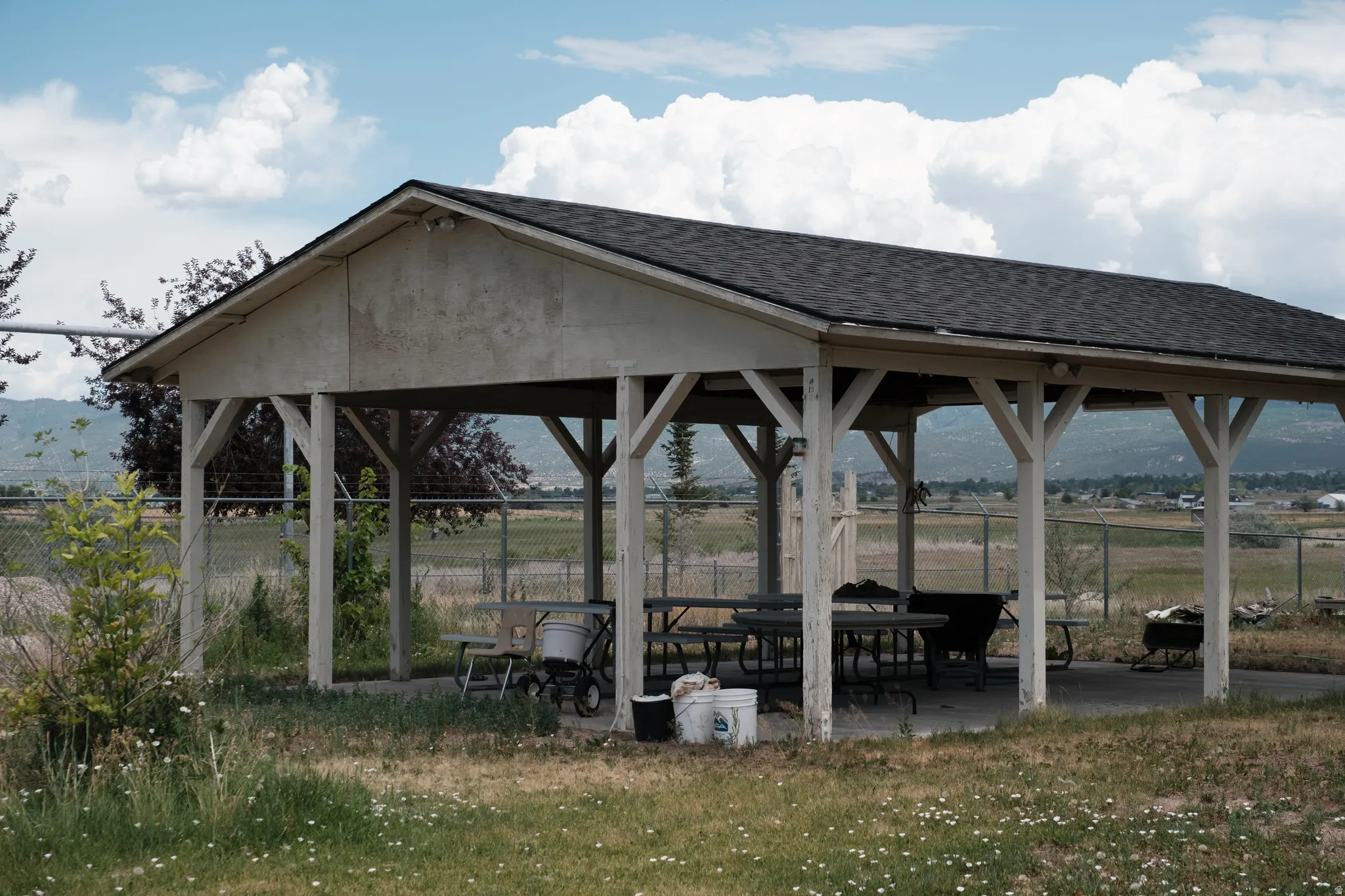 Outdoor covered patio structure with a dark shingle roof and exposed support beams