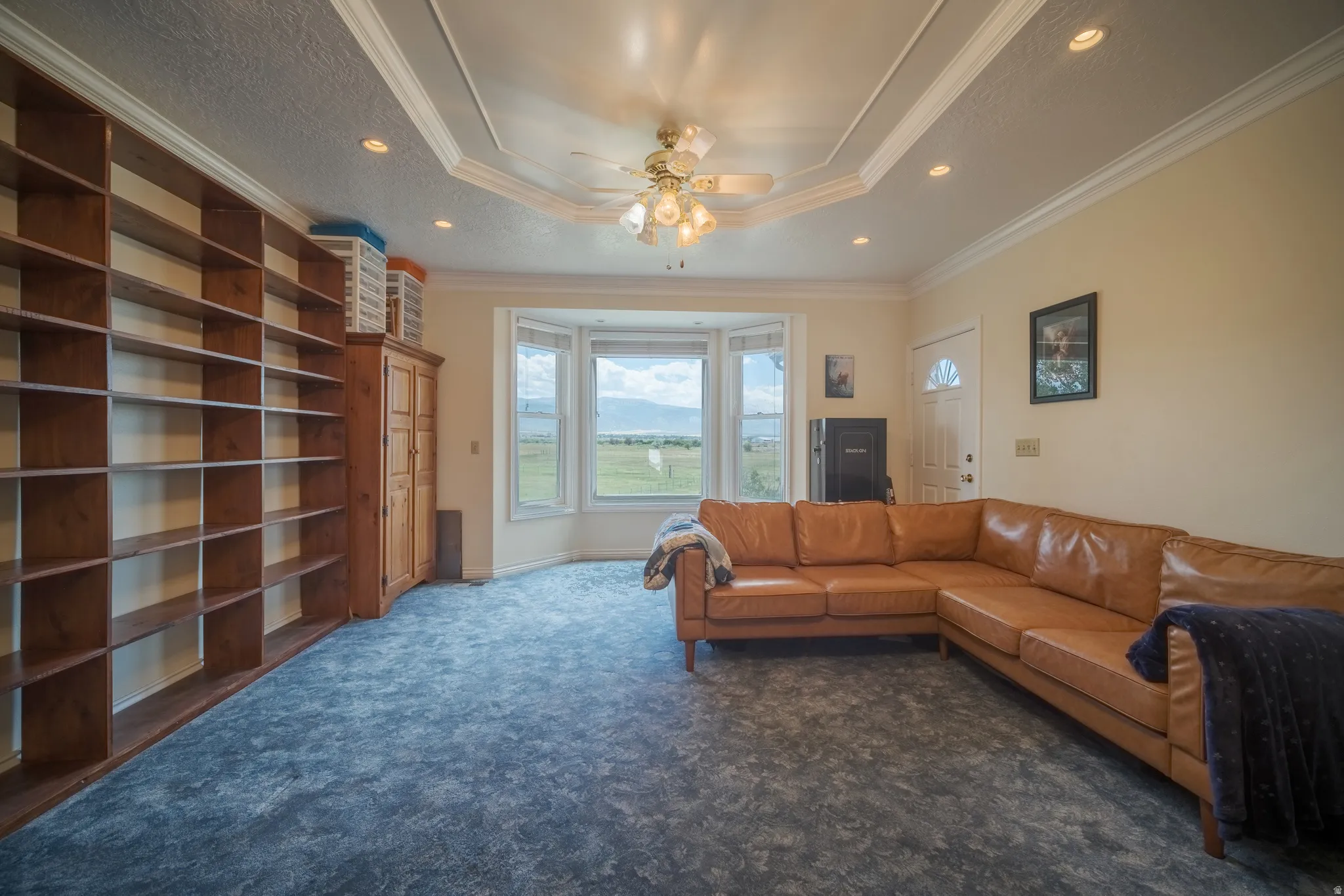 Spacious room featuring a tray ceiling, recessed lighting, and a bay window