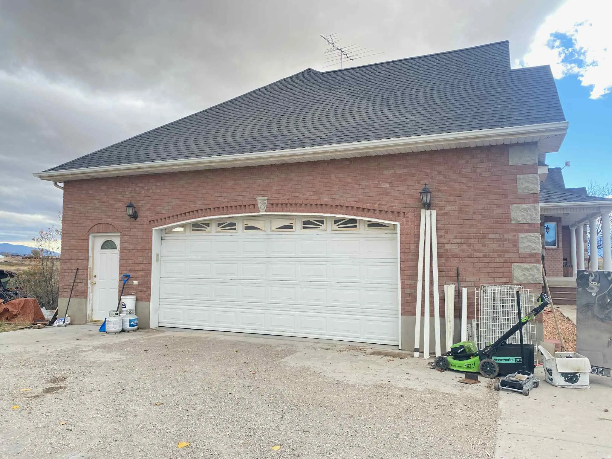 View of property exterior with brick siding, roof with shingles, and driveway