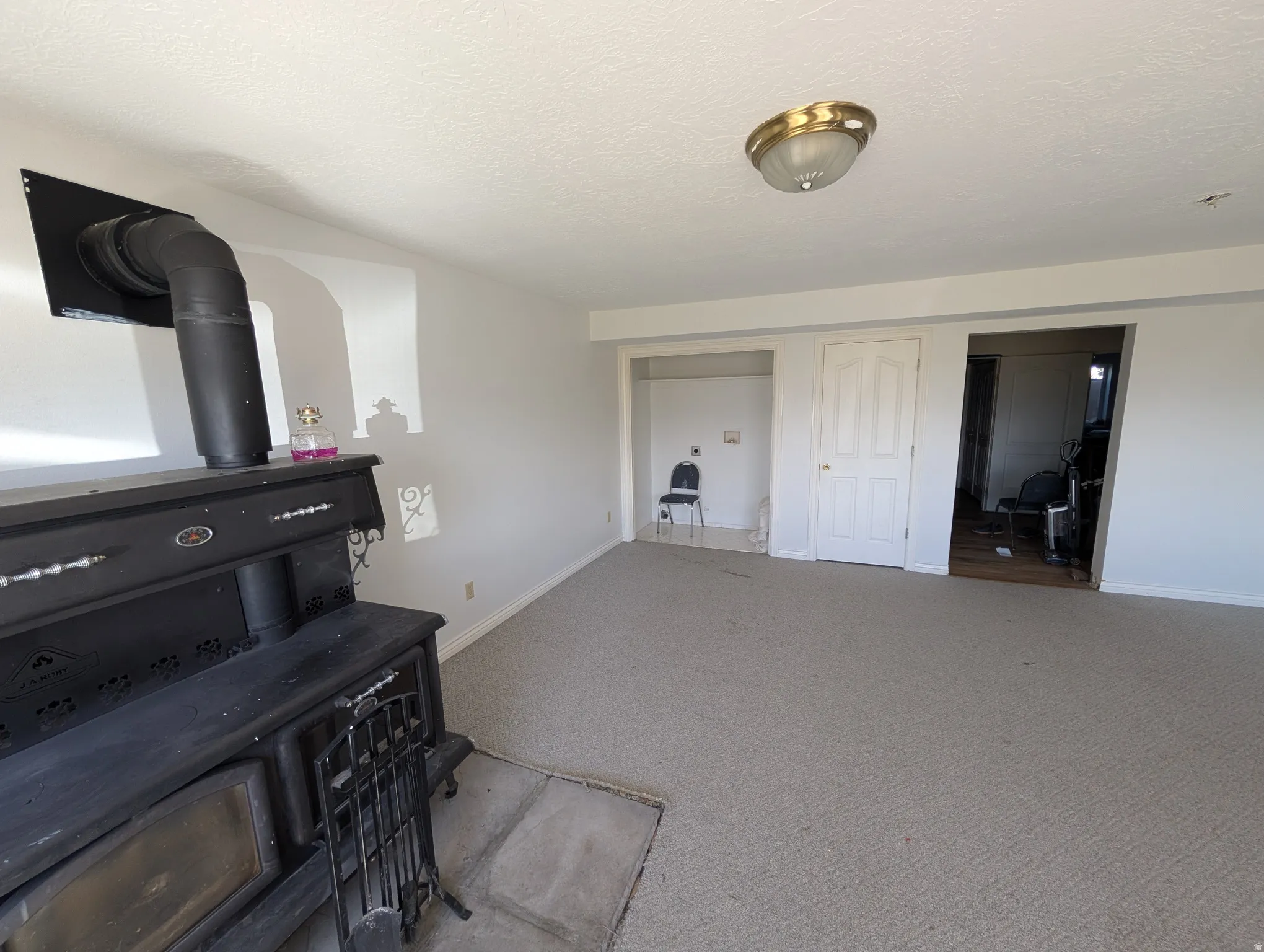 Carpeted bedroom with a textured ceiling and a wood stove