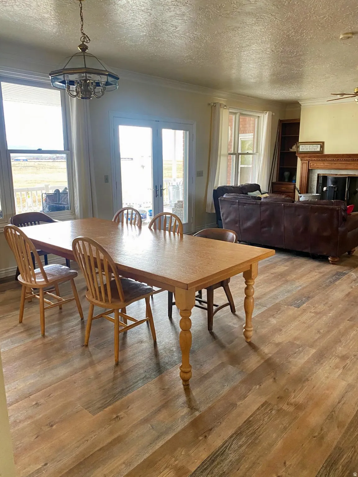 Dining room featuring a textured ceiling, plenty of natural light, a chandelier, light wood-style floors, and ornamental molding