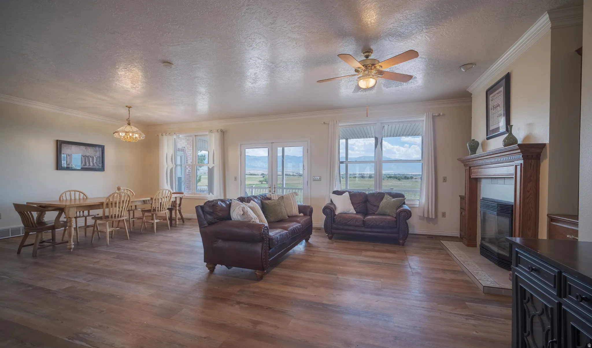 Spacious living area featuring wood-finish flooring, crown molding, and a built-in fireplace with a wood mantel