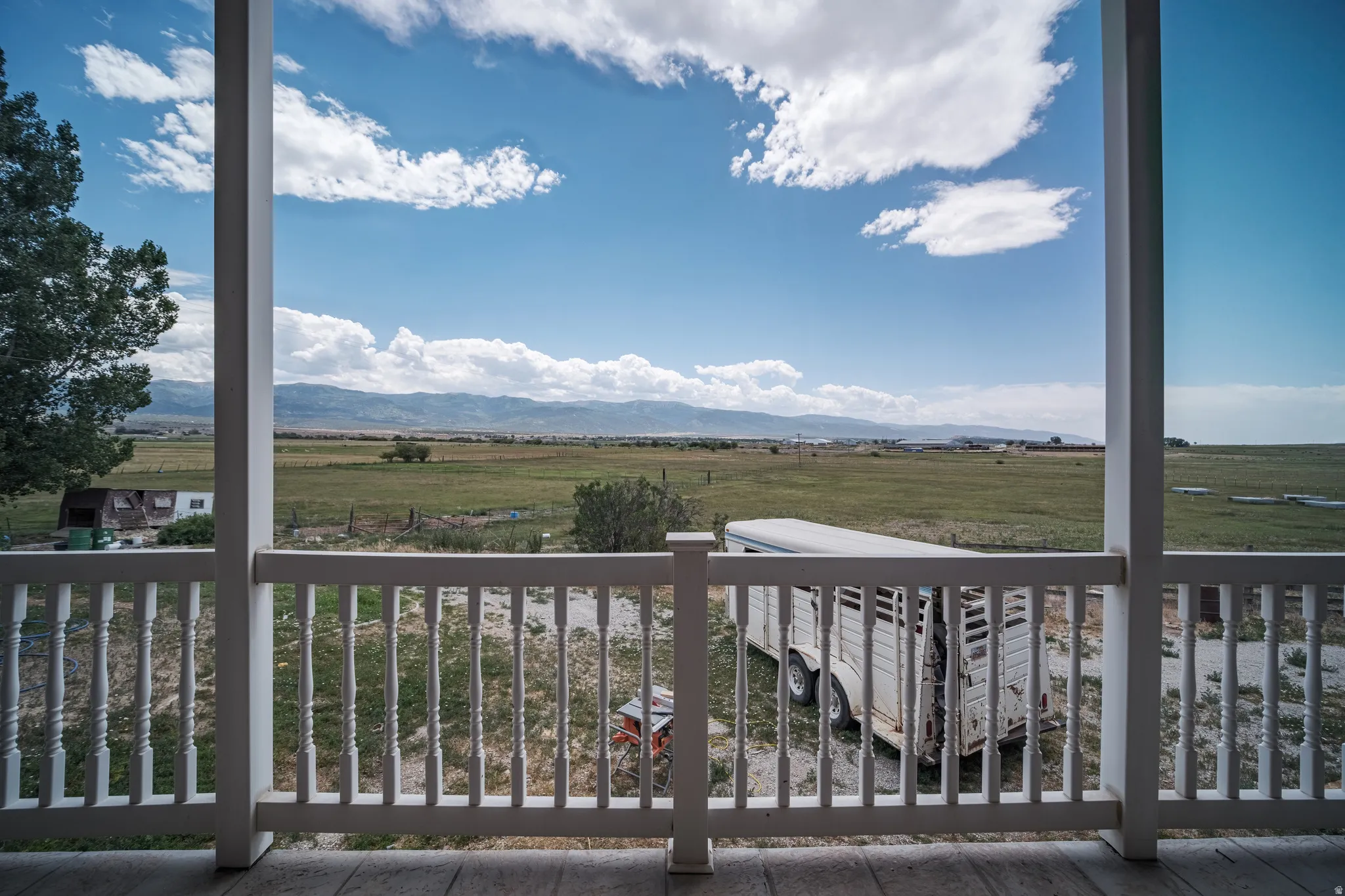 Expansive pastoral landscape framed by a white baluster railing and columns