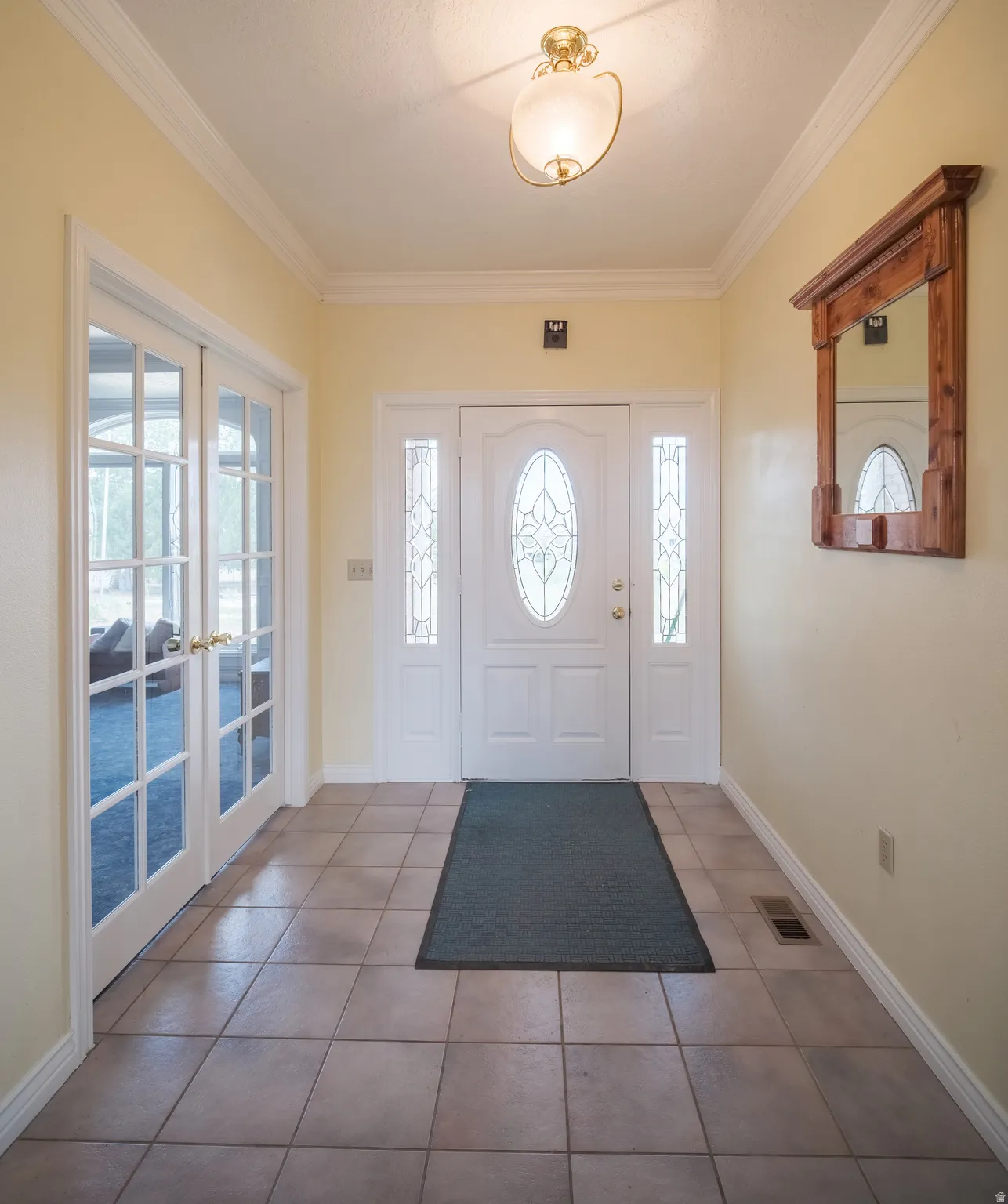 Entryway featuring light-toned tile flooring, a white front door with leaded glass oval, and sidelight windows
