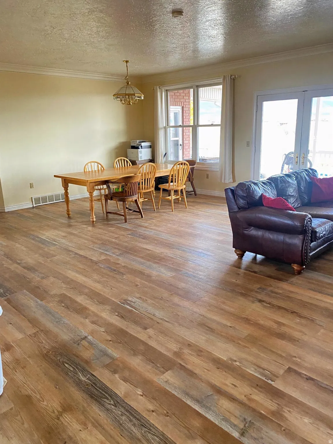 Dining space featuring a textured ceiling, crown molding, and wood-type flooring
