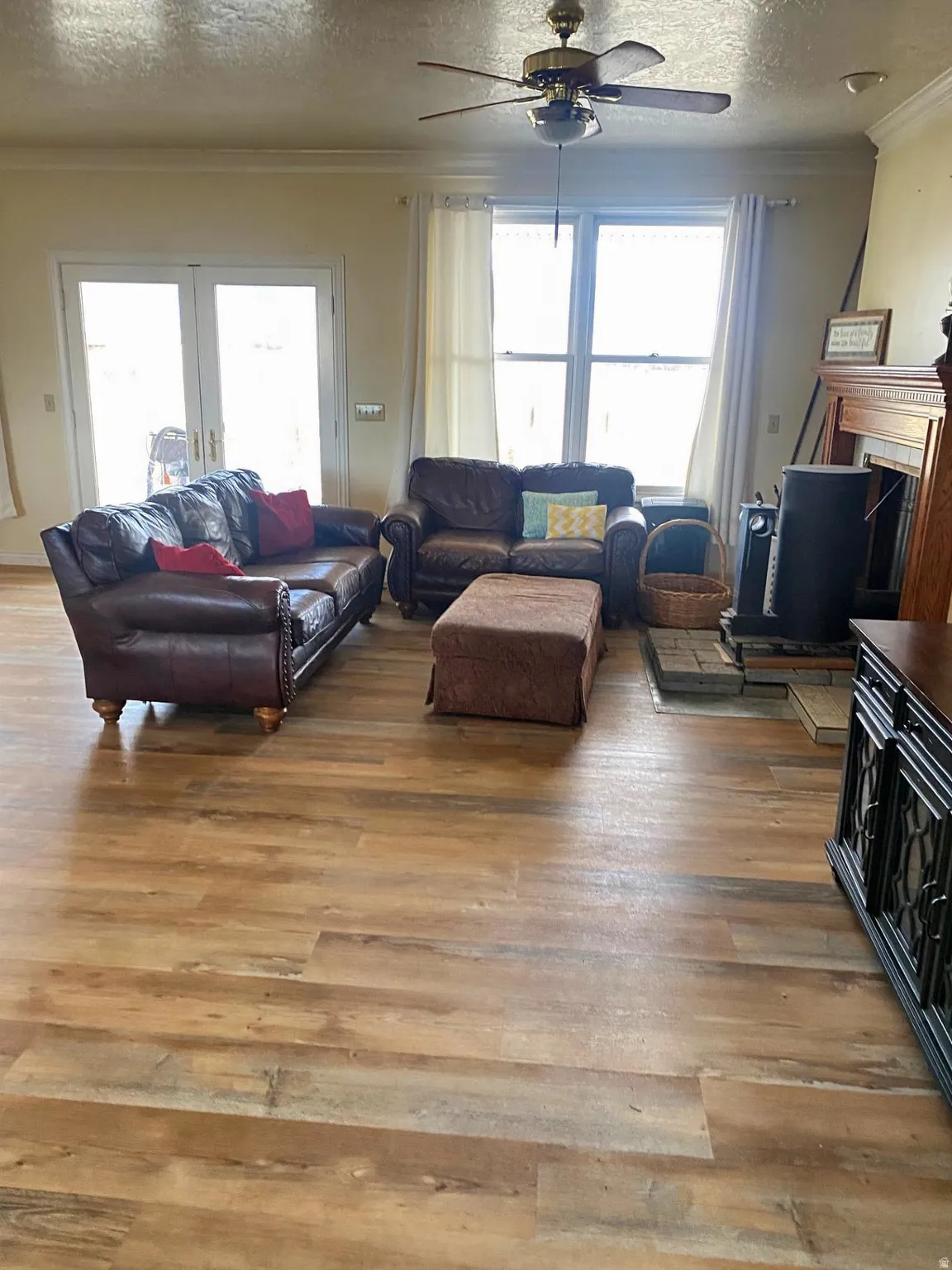 Living area featuring a textured ceiling, ornamental molding, light wood-style flooring, plenty of natural light, and a fireplace